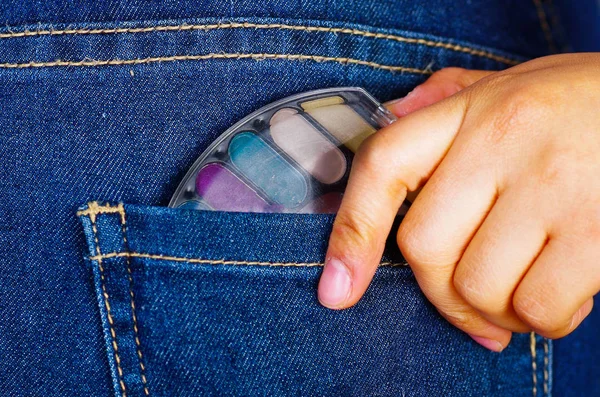 Mano de mujer sosteniendo una paleta de maquillaje dentro del bolsillo trasero de los vaqueros —  Fotos de Stock