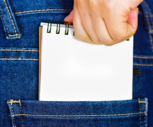 Mano de mujer poniendo un cuaderno pequeño blanco dentro del bolsillo trasero de los pantalones vaqueros —  Fotos de Stock