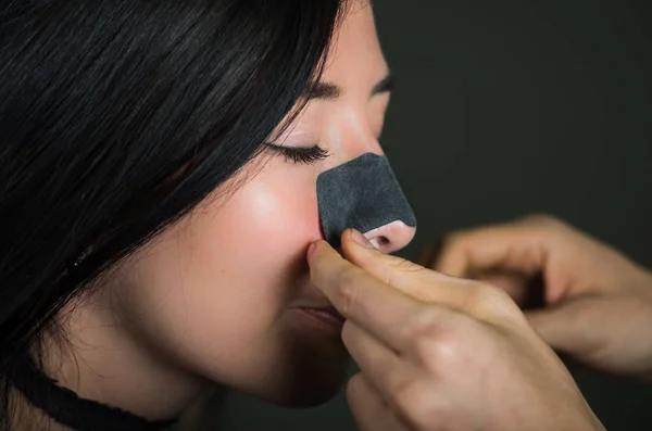 Piękna młoda kobieta aplying czarny nos maskę do czyszczenia skóry z czarnymi plamami — Zdjęcie stockowe