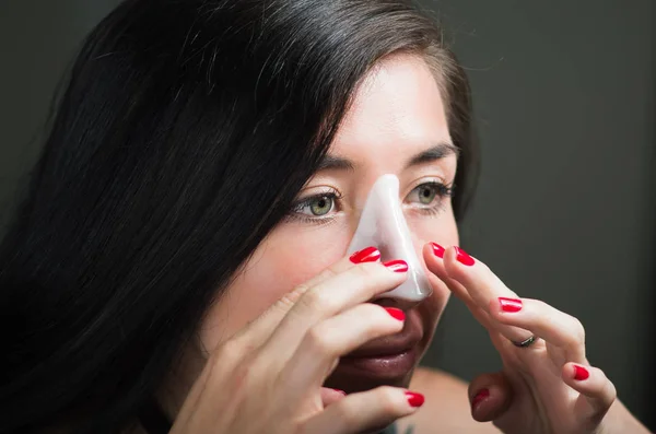 Piękna młoda kobieta aplying biały nos maskę do czyszczenia skóry — Zdjęcie stockowe