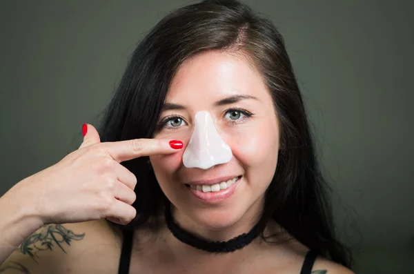 Piękna młoda kobieta wskazując w od jej nos maskę otwarty białego nosa do czyszczenia skóry — Zdjęcie stockowe