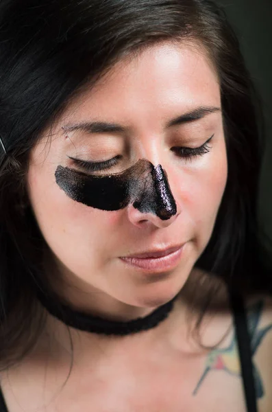 Gros plan d'une belle jeune femme aplatissant un masque noir pour nettoyer la peau — Photo