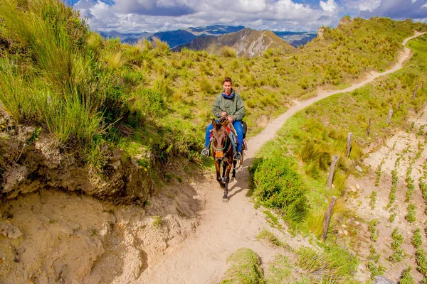 Quito, Ecuador - November, 25 2016: Azonosítatlan fiatal turista lovaglás egy ló trought a homokos út Quilotoa inaktív vulkán közelében. Quilotoa a nyugati vulkán körű Andokban, és található — Stock Fotó