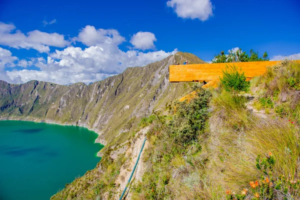 QUITO, ECUADOR - NOVEMBER, 25 2016: Unidentified people enjoying the view of lake with a beautiful magenta color of the Quilotoa caldera from a wooden structure lookout. Quilotoa is the western — Stock Photo, Image