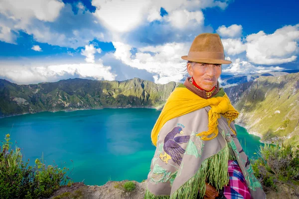 QUITO, ECUADOR - 25 DE NOVIEMBRE DE 2016: Anciana indígena no identificada vestida con una típica ropa andina frente al lago Quilotoa con un hermoso color magenta de la caldera Quilotoa. Quilotoa es — Foto de Stock