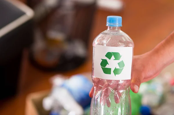 Zbliżenie ręki trzymającej plastikowej butelce ze znakiem wydruku recyklingu w przód, przerabianie surowców wtórnych i bezpiecznego świata od globalnego ocieplenia koncepcji — Zdjęcie stockowe
