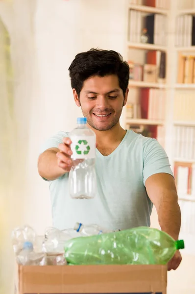 Joven poniendo una botella de plástico dentro de una caja de cartón llena de plástico, recicla y salva al mundo del concepto de calentamiento global —  Fotos de Stock