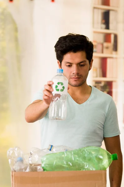 Genç adam bir plastik şişe plastik, geri dönüşüm ve güvenli dünya dolu bir karton kutu içinde küresel ısınma konseptinden koyarak. — Stok fotoğraf