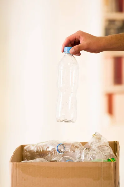 Zbliżenie dłoni wprowadzenie plastikowej butelce wewnątrz kartonowe pudełko z tworzyw sztucznych, recyklingu i bezpieczny świat od globalnego ocieplenia koncepcji — Zdjęcie stockowe
