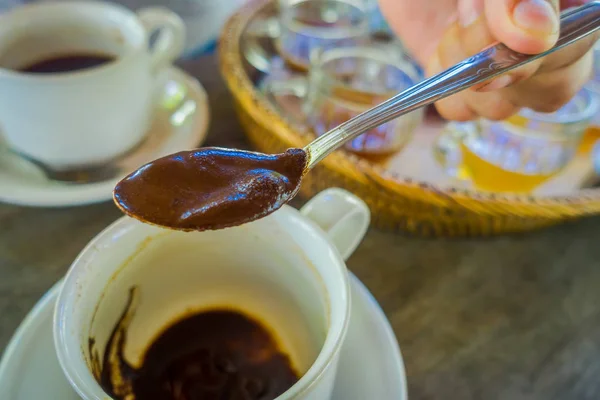 Ajouter à la main avec une cuillère un café Kopi Luwak de la plantation à Bali, Indonésie, sur fond de bois — Photo