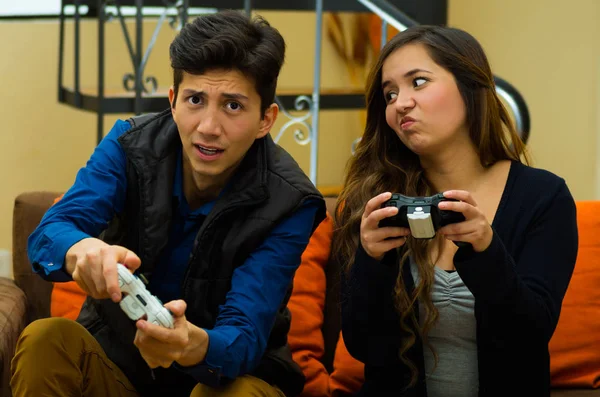 Knappe jongeman spelen van videospellen, vrouw met een verveeld expresion in haar gezicht, op de Bank, concept over huisvermaak, video games — Stockfoto