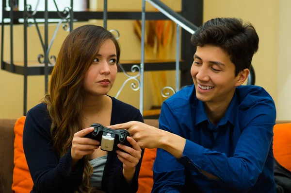 Handsome young man teaching how to play the video games to his bored girlfriend, on the couch, concept about home entertainment, video games — Stock Photo, Image