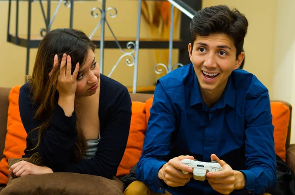 Handsome young man playing video games on the couch while girlfriend is bored, concept about home entertainment, video games — Stock Photo, Image