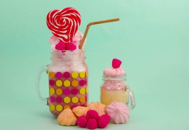 Lezzetli ev yapımı aşırı milkshake bir süt üzerinde blackberry şeker ile bir kavanoz içinde çilek, köpük plastik hasır ve üstte, yumuşak mavi kalp şeker pembe blackberry şekerle