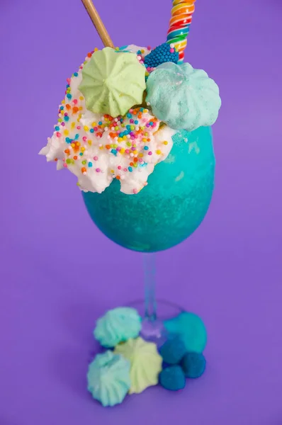 Läcker hemmagjord extrema milkshake med dragéer över ett mjölkskum, i en lila bakgrund — Stockfoto