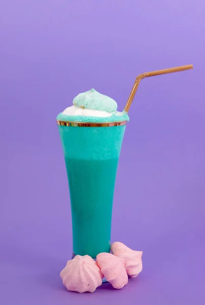 Läcker hemmagjord extrema milkshake med mjölkskum på toppen med en plast halm i en lila bakgrund — Stockfoto