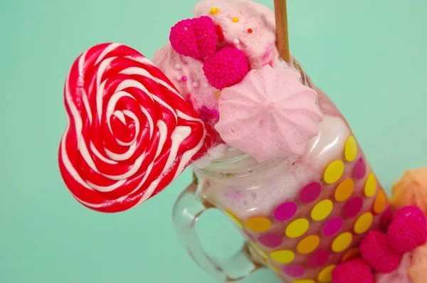 在关闭美味的自制极端奶昔的草莓在罐子里，在一根塑料吸管牛奶泡沫的黑莓糖果和顶上，心糖果粉红色黑莓糖果 — 图库照片