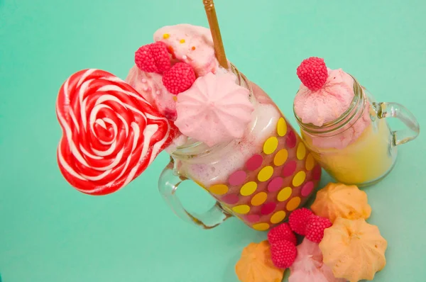 Close up of a delicious homemade extreme milkshake of strawberry in a jar, with a blackberry candy over a milk foam with a plastic straw and a pink blackberry candy with a heart candy on top, in a — Stock Photo, Image