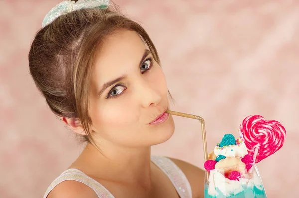 Close up of a pretty cute woman drinking tasty blue milk shake, in a pink background — Stock Photo, Image