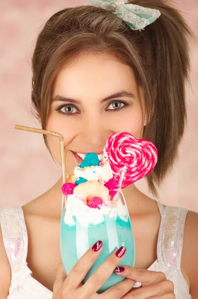 Zbliżenie na całkiem cute kobietę smaczny niebieski milk shake z serca cukierki na górze, modne ciuchy, moda studio w różowym tle — Zdjęcie stockowe