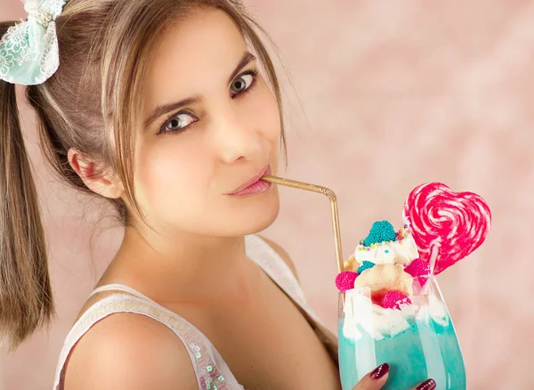Primo piano di una bella donna carina che beve gustoso frullato di latte blu, in uno sfondo rosa — Foto Stock