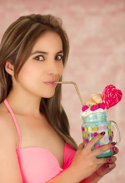 Close up van een vrij leuke vrouw lekker blauwe milkshake drinken in een pot, in een roze achtergrond — Stockfoto