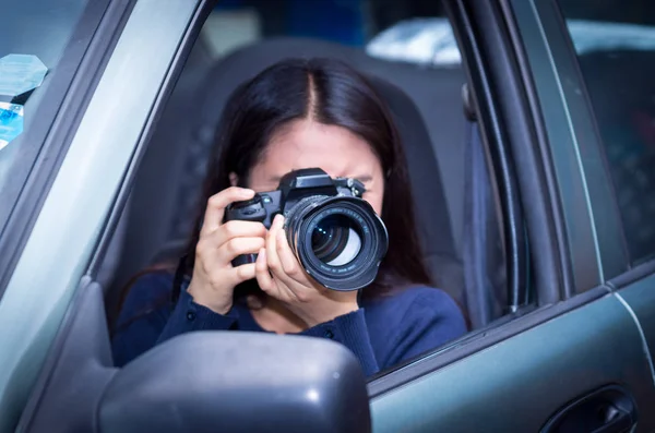 Young woman stalking and taking pictures with her camera, inside of her car — Stock Photo, Image