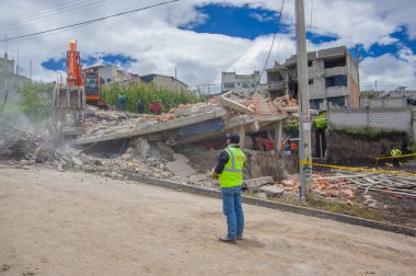 Quito, Ekvator - Nisan, 17, 2016: deprem ve afet, genç bir adamla Quito, Ekvator sürecinde gözlemleyerek temizlik ağır makine tarafından yok evi