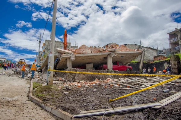 Кито, Эквадор - 17 апреля 2016 года: Дом, разрушенный землетрясением, с красной машиной, пойманной под разрушенное строительство, и тяжелой техникой, очищающей город Кито, Эквадор — стоковое фото