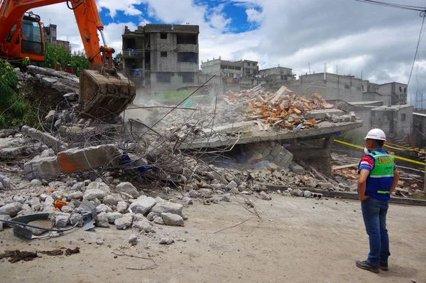 Quito, Ekvator - Nisan, 17, 2016: deprem ve afet, genç bir adamla Quito, Ekvator sürecinde gözlemleyerek temizlik ağır makine tarafından yok evi
