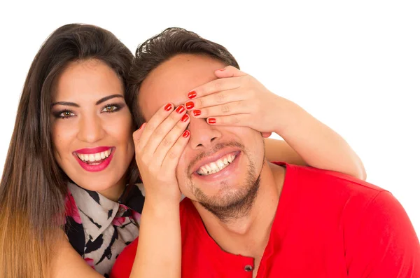 Primer plano de feliz pareja aislada sobre fondo blanco. Atractivo hombre y mujer siendo juguetón, mujer poniendo sus manos sobre los ojos de su novio — Foto de Stock