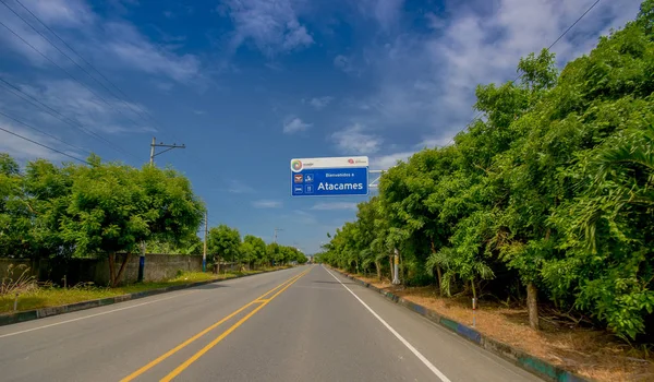 Asphaltierte Straße an der Küste, mit informativen Schildern, umgeben von üppiger Vegetation an einem sonnigen Tag an der ecuadorianischen Küste — Stockfoto