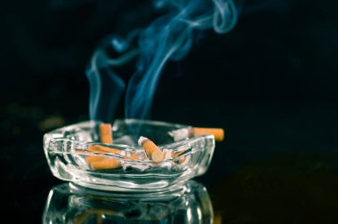 Kristal kül tablası siyah arka plan üzerinde sigara tüketilen