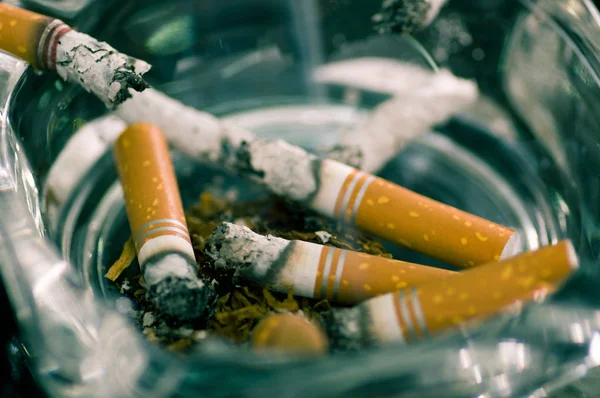 Close up of consumed cigarettes over a crystal ashtray — Stock Photo, Image