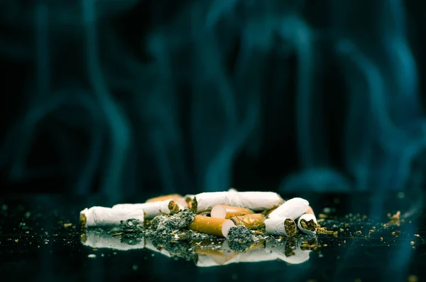 Verbruikte sigaretten met ash op een zwarte achtergrond — Stockfoto
