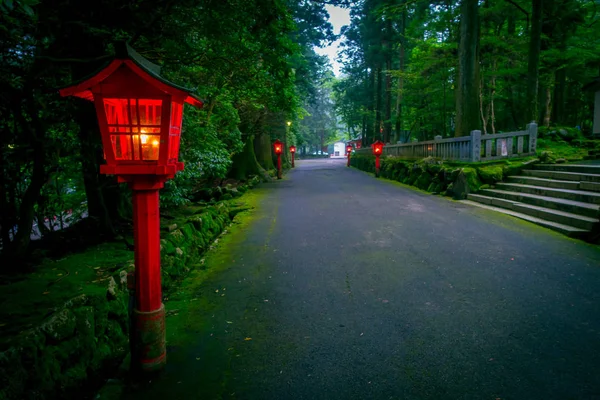 La vista nocturna del acercamiento al santuario de Hakone en un bosque de cedro. Con muchos faroles rojos iluminados —  Fotos de Stock