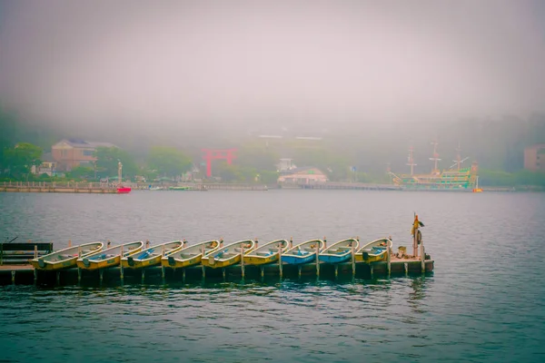 HAKONE, JAPÓN - 02 DE JULIO DE 2017: Barcos de pesca y puerta Torii rojo del santuario de Hakone en el lago Ashi en el día de niebla — Foto de Stock