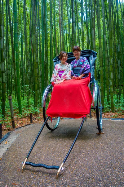 KYOTO, JAPAN - JULY 05, 2017: Unidentified people over a red rickshaw in a path at beatiful bamboo forest at Arashiyama, Kyoto, Japan — Stock Photo, Image