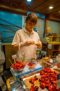 Kyoto, Japonya - 05 Temmuz 2017: onun elinde tutan kimliği belirsiz kadın haşlanmış küçük ahtapot Nishiki pazarı Kyoto, satılan