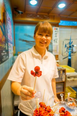 Kyoto, Japonya - 05 Temmuz 2017: onun elinde tutan kimliği belirsiz kadın haşlanmış küçük ahtapot Nishiki pazarı Kyoto, satılan