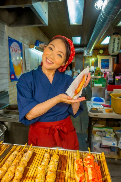 Kyoto, Japonya - 05 Temmuz 2017: Kyoto Nishiki markette satılan bir brochette elinde tutan kimliği belirsiz gülümseyen kadın