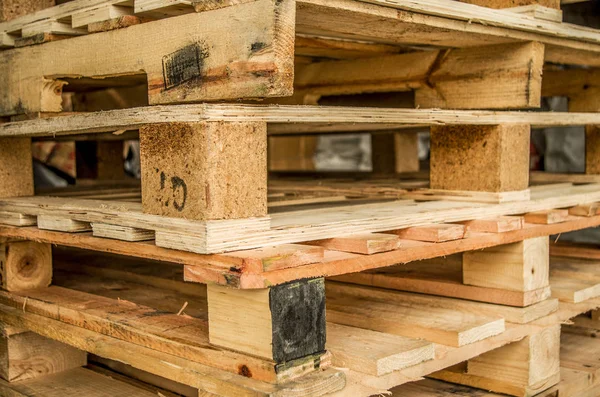 Buiten vervaardigd voorraad van oude houten standaard europallets opgeslagen in pylonen — Stockfoto