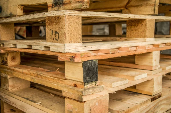 Buiten vervaardigd voorraad van oude houten standaard europallets opgeslagen in pylonen — Stockfoto