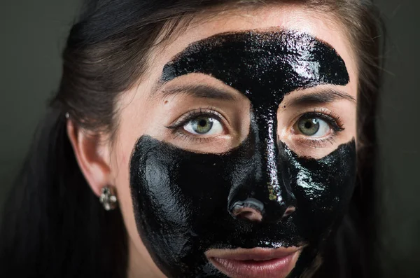 Close up de uma beleza jovem mulher usando uma máscara preta para limpar a pele — Fotografia de Stock