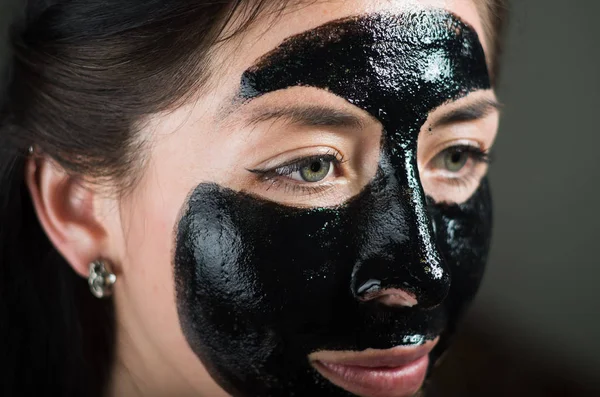Närbild av en skönhet ung kvinna med en svart mask rengör huden — Stockfoto