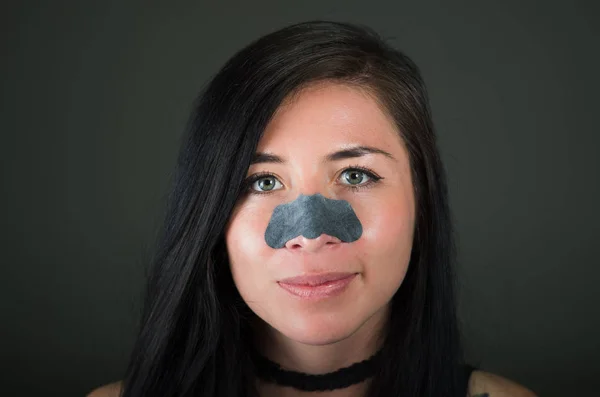 Beleza jovem aplying uma máscara de nariz preto para limpar a pele de manchas pretas — Fotografia de Stock