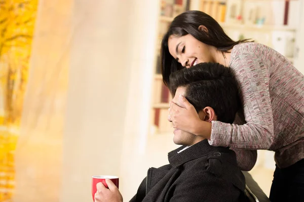 Schönes junges verliebtes Paar, Freundin bedeckt die Augen seines Freundes im Hintergrund des Büros — Stockfoto