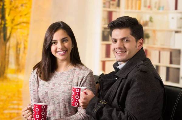 St Sevgililer günü, bir fincan kahve bir bulanık arka planda tutarak aşık güzel genç Çift — Stok fotoğraf