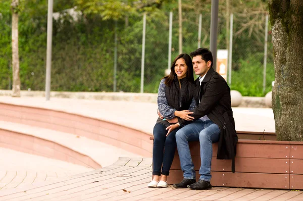 Beautiful young couple in love in st valentines day sitting in a park — Stock Photo, Image