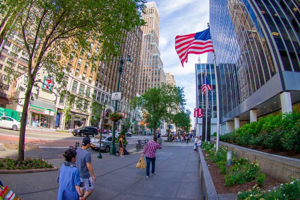 NEW YORK, États-Unis - 22 JUIN 2017 : Des personnes non identifiées marchent dans la belle ville de New York avec des gratte-ciel et de magnifiques bâtiments à New York, aux États-Unis, avec un drapeau américain tenant d'un bâtiment — Photo